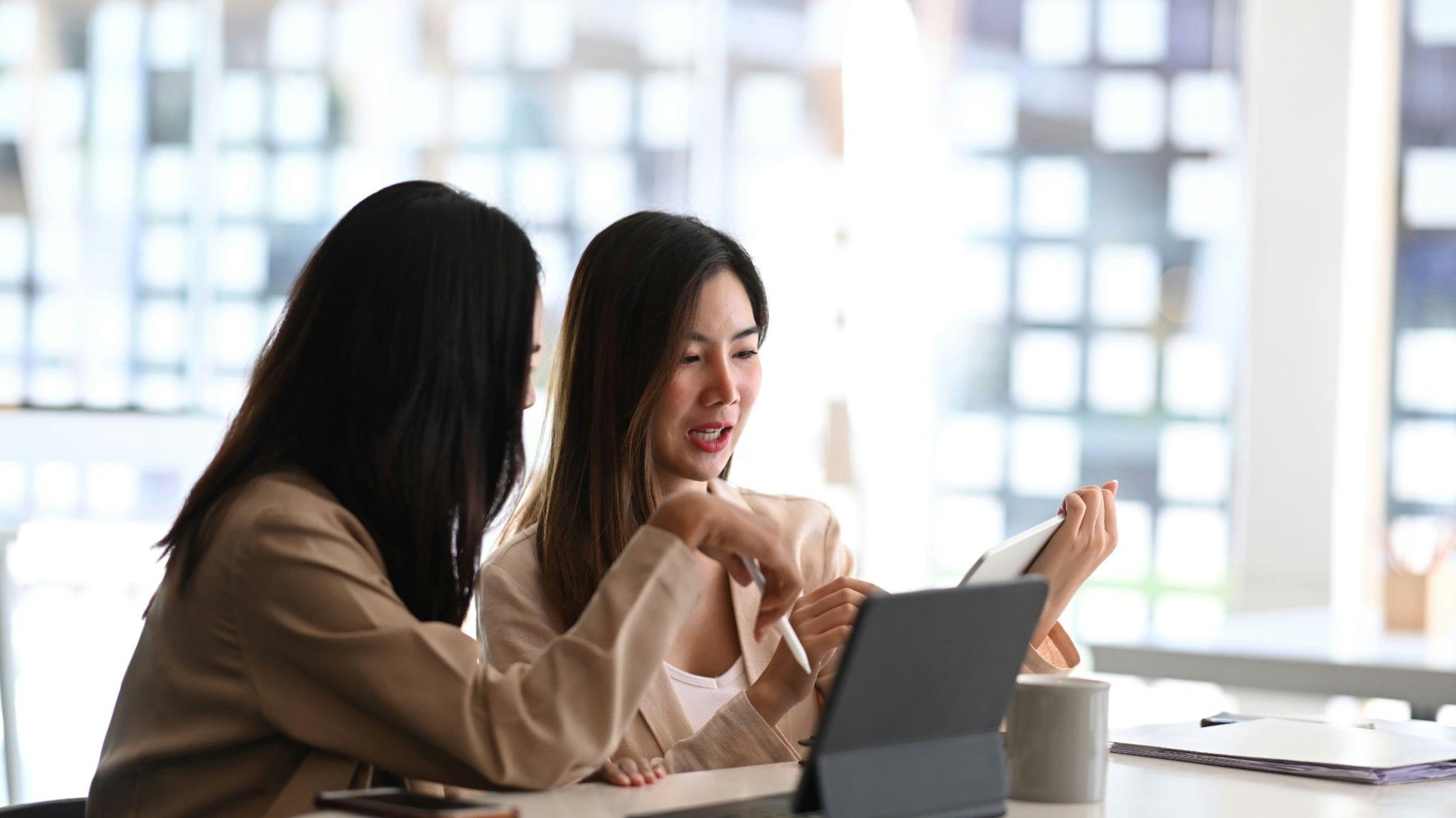 Colleagues collaborating over a tablet in a bright office